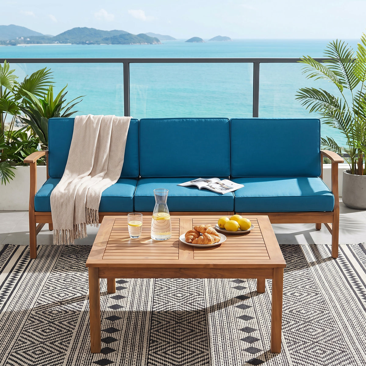 Perla Acacia Wood Outdoor Sofa and Table Set with blue cushions on balcony overlooking sea on Tampa Home & Garden Store
