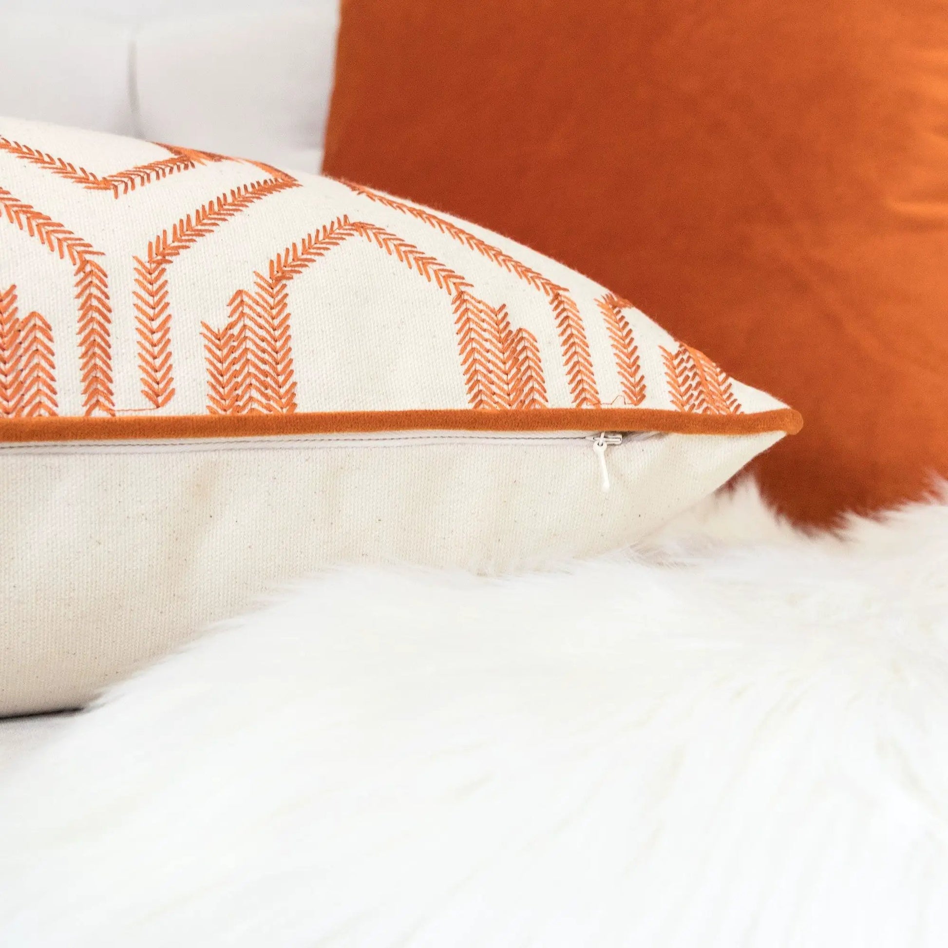 Geometric embroidered rust orange throw pillow with white base and piped edge on Tampa Home & Garden Store