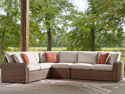 Dolan Creek Outdoor Sectional by Unique Piece beige cushions on brown wicker with red pillows on Tampa Home & Garden Store