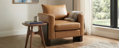 Modern accent chair with tan leather upholstery and rubberwood legs in living room setting on Tampa Home & Garden Store