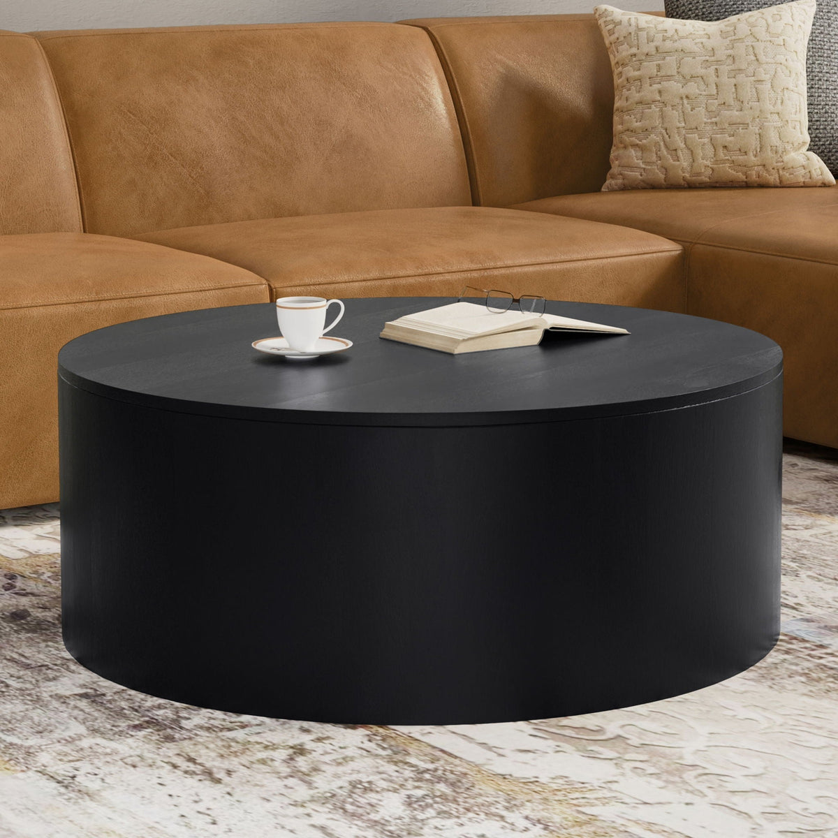 Millbury Drum Coffee Table in black with a white cup and saucer, open book, and glasses on Tampa Home & Garden Store