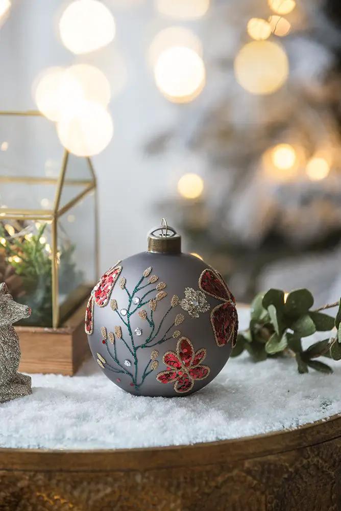 Gray glass hanging ball ornament with red and gold embroidery on snow surface Unique Piece on Tampa Home & Garden Store