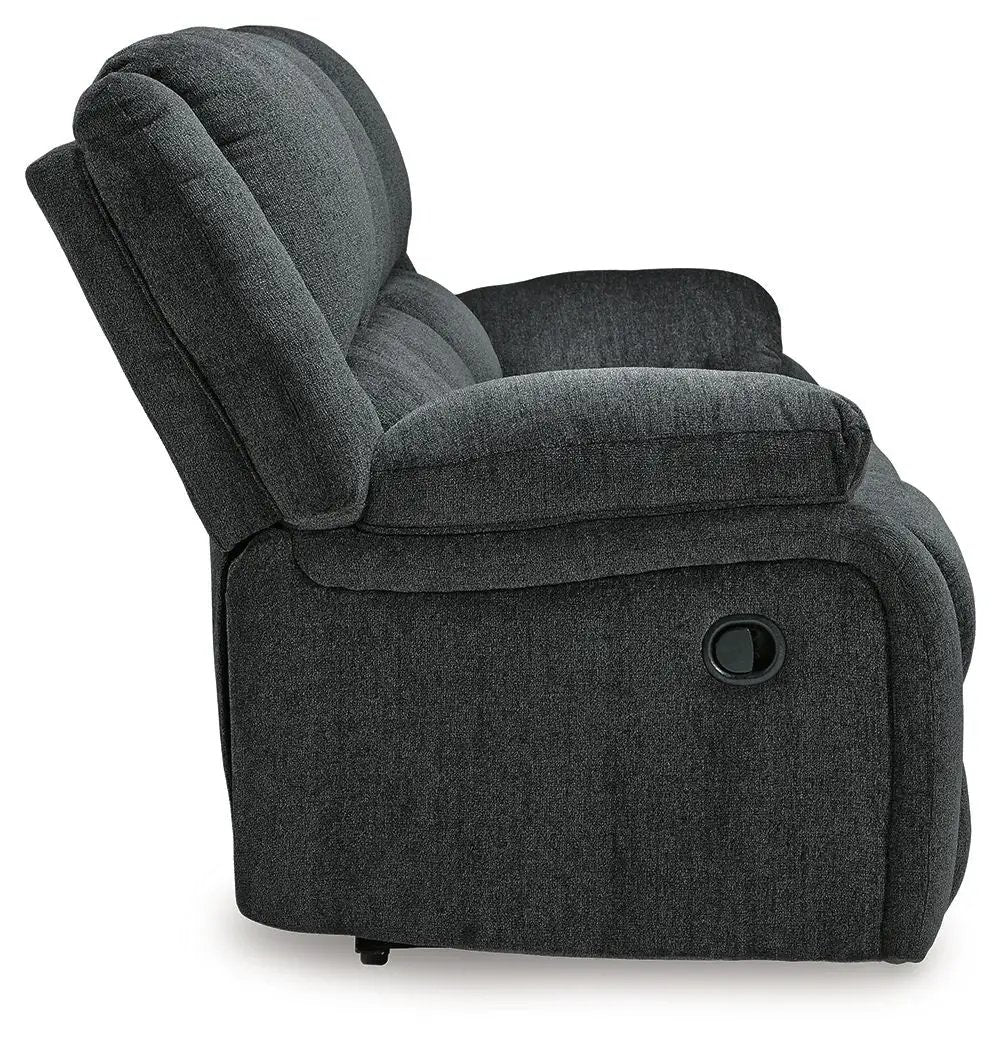 Draycoll reclining sofa in dark charcoal fabric with plush cushions and side lever on Tampa Home & Garden Store