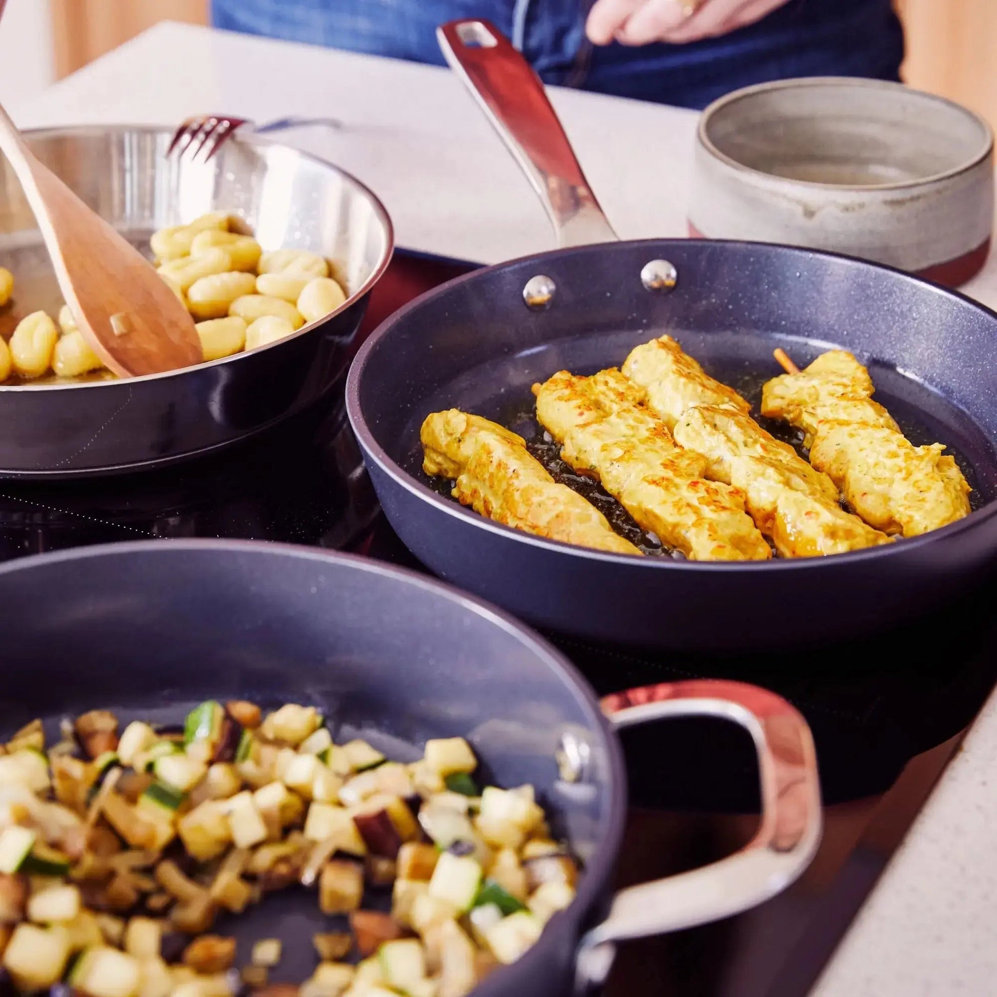 Ceramic nonstick cookware set on a stovetop; pans show browned chicken and diced vegetables on Tampa Home & Garden Store