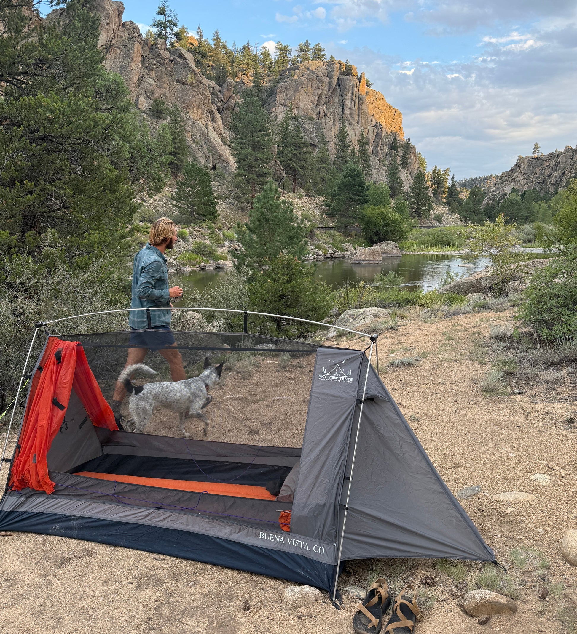 Sky View Solo Tent gray with orange accents set by a rocky river canyon with a man and two dogs on Tampa Home & Garden Store