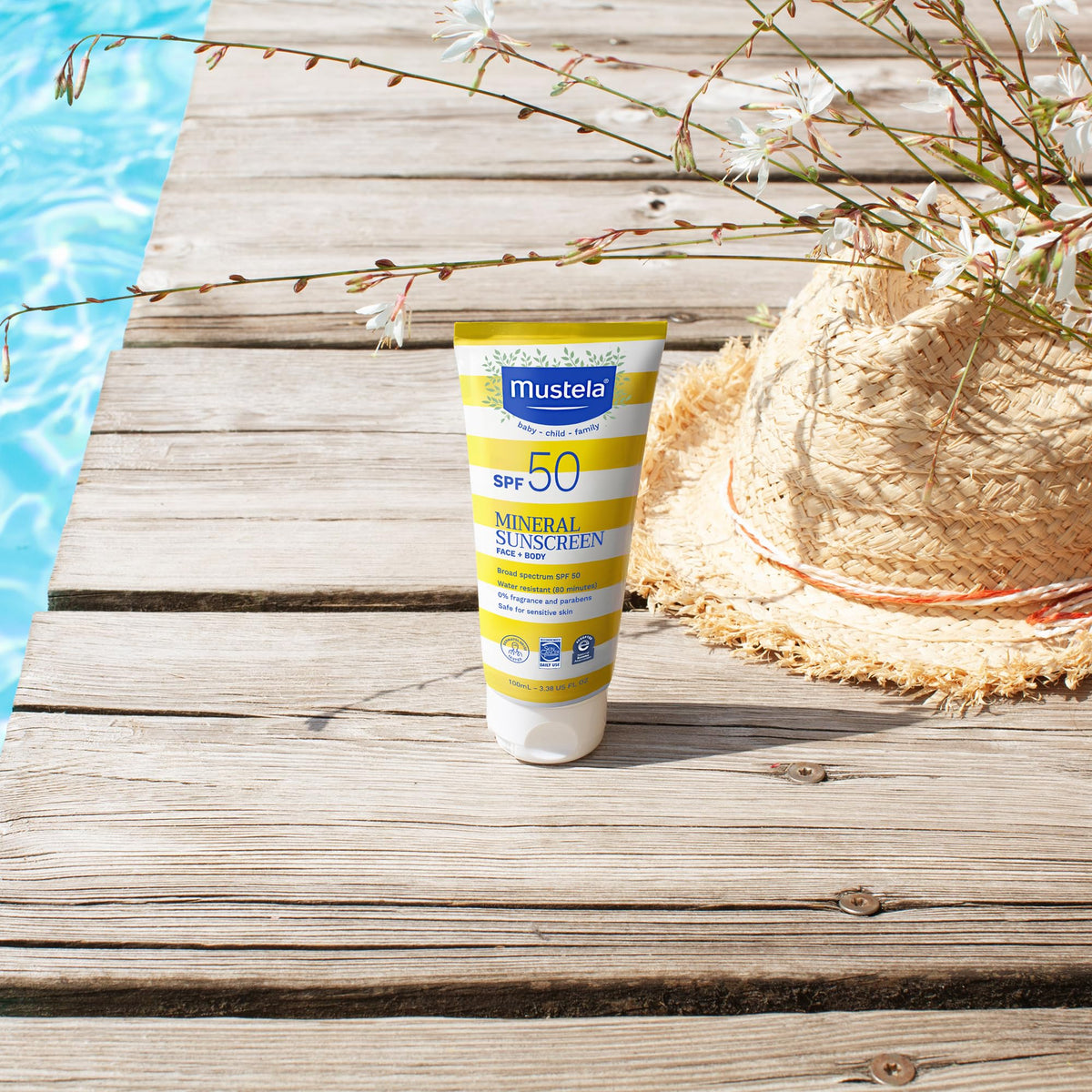 Mustela SPF 50 Face Sunscreen in yellow and white tube on a wooden deck with a straw hat on Tampa Home & Garden Store