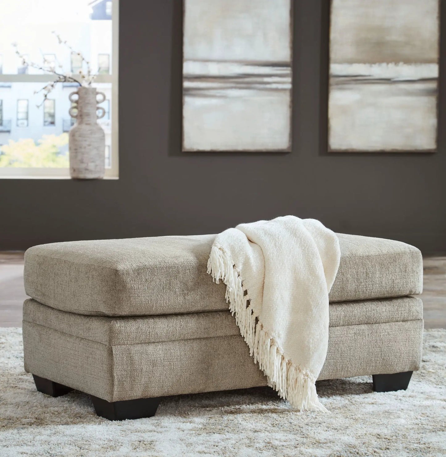 Stonemeade living room ottoman in beige textured fabric with cream knitted throw on Tampa Home & Garden Store