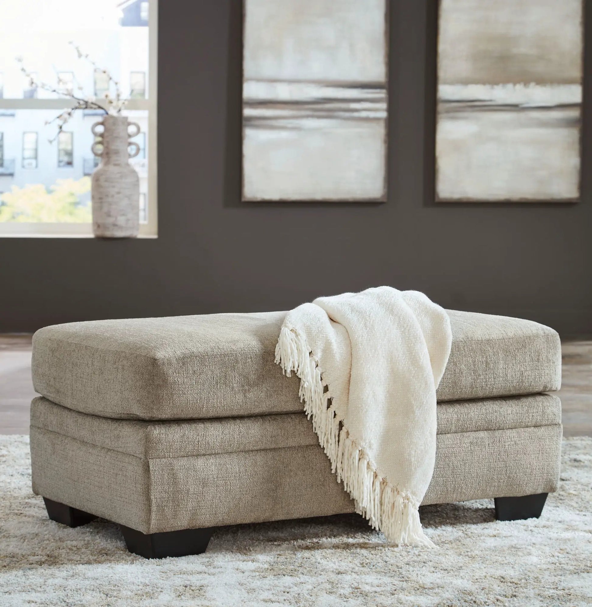Stonemeade living room ottoman in beige textured fabric with cream knitted throw on Tampa Home & Garden Store