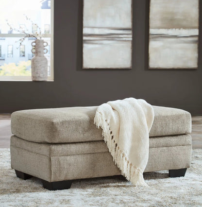 Stonemeade living room ottoman in beige textured fabric with cream knitted throw on Tampa Home & Garden Store