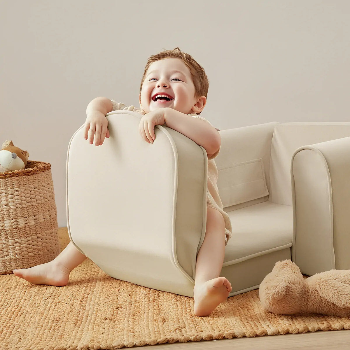 Tiny Land GentleSnug Kid Chair beige fabric, child perched and smiling in a cozy playroom on Tampa Home & Garden Store