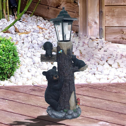 Black bear garden statue with a solar lantern atop a textured tree trunk and a Welcome sign on Tampa Home & Garden Store