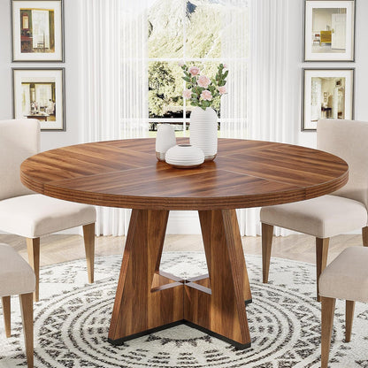 Round wooden dining table with cross pedestal base, beige chairs and white ribbed vases on Tampa Home & Garden Store