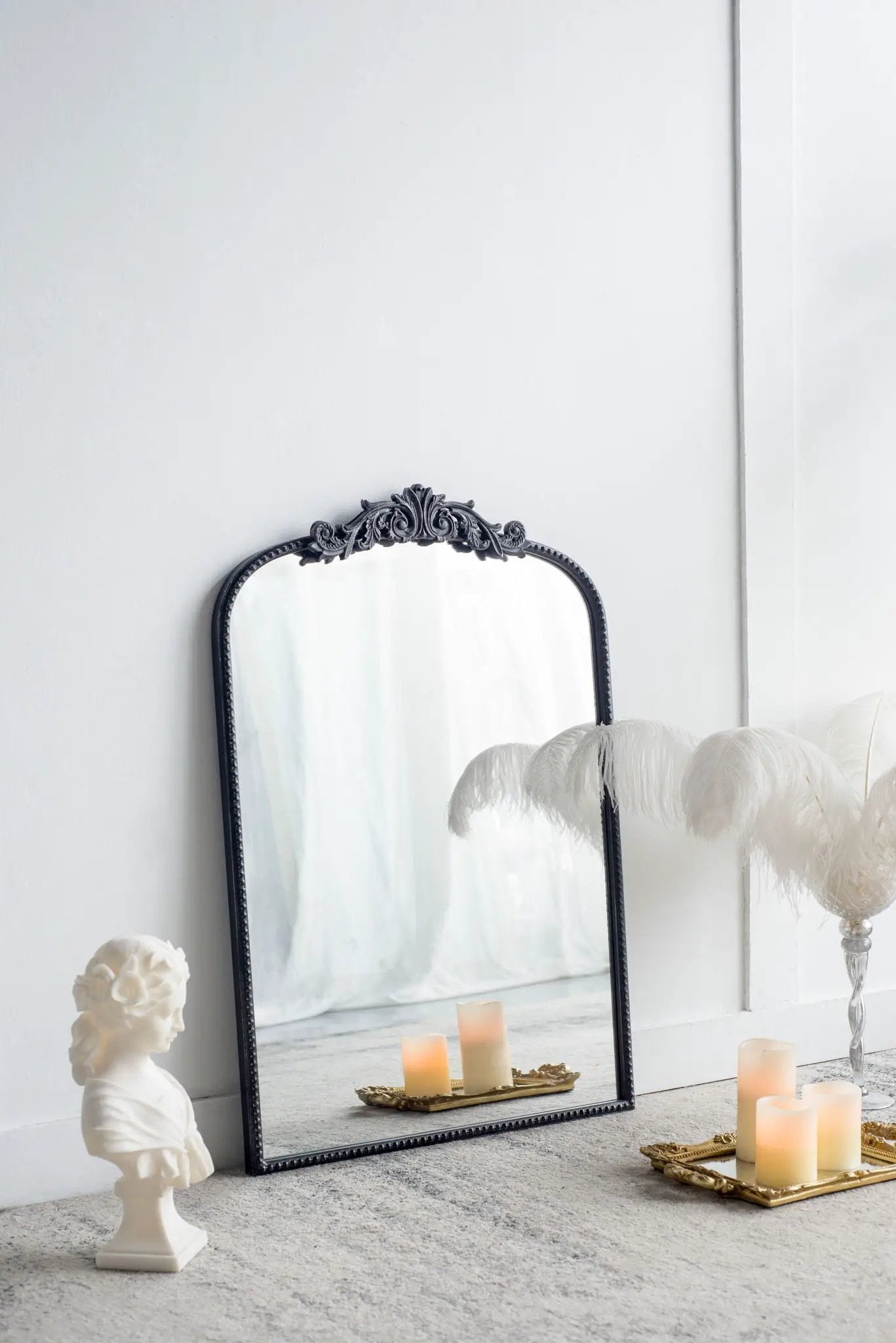 Arch Mirror with a black Baroque ornate frame leaning on white wall, candles on a tray on Tampa Home & Garden Store
