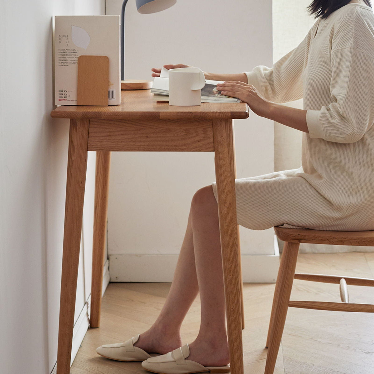 Oak computer desk with drawer in natural wood finish, person seated at desk with white mug on Tampa Home & Garden Store