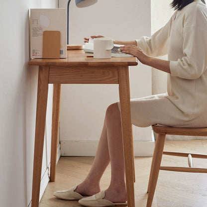 Oak computer desk with drawer in natural wood finish, person seated at desk with white mug on Tampa Home & Garden Store