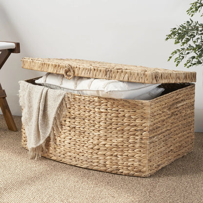 Rectangular water hyacinth woven storage trunk with handles in natural light brown, beige blanket draped over edge on Tampa Home & Garden Store