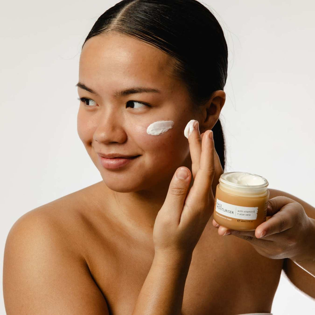 UpCircle Face Moisturiser jar amber with white lid; vitamin E; applying cream to cheek on Tampa Home & Garden Store