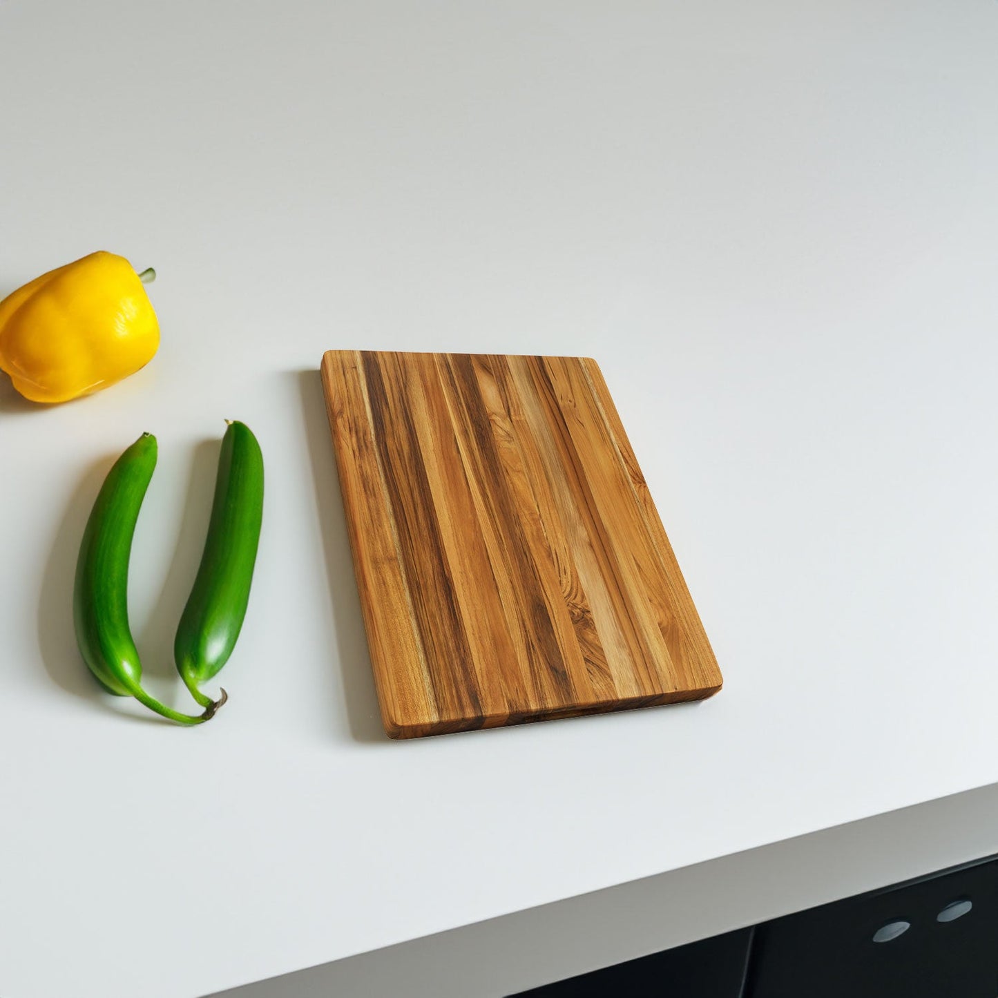 Teak cutting board natural wood with striped grain 18 inch on white surface beside yellow pepper on Tampa Home & Garden Store