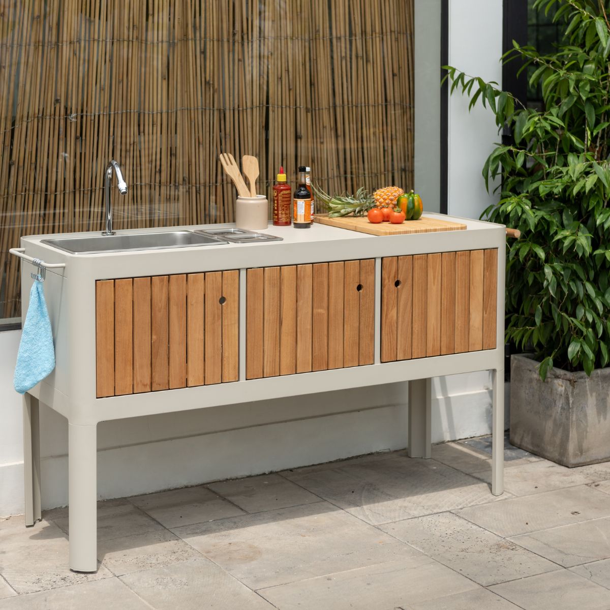 Portals Light Outdoor Kitchen gray frame with wood slat doors, sink, cutting board with pineapple on Tampa Home & Garden Store