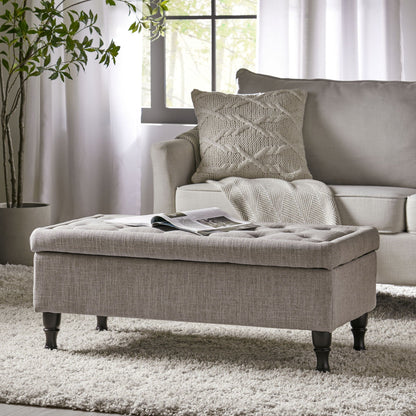 Wide tufted gray fabric storage ottoman with concealed storage and dark turned feet on Tampa Home & Garden Store
