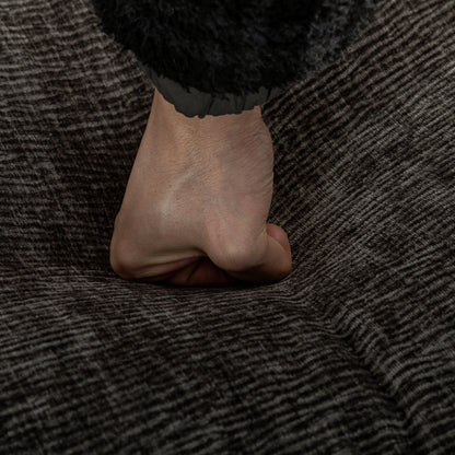 Close-up of a hand grasping a black ruffled sleeve against dark textured upholstery on Tampa Home & Garden Store