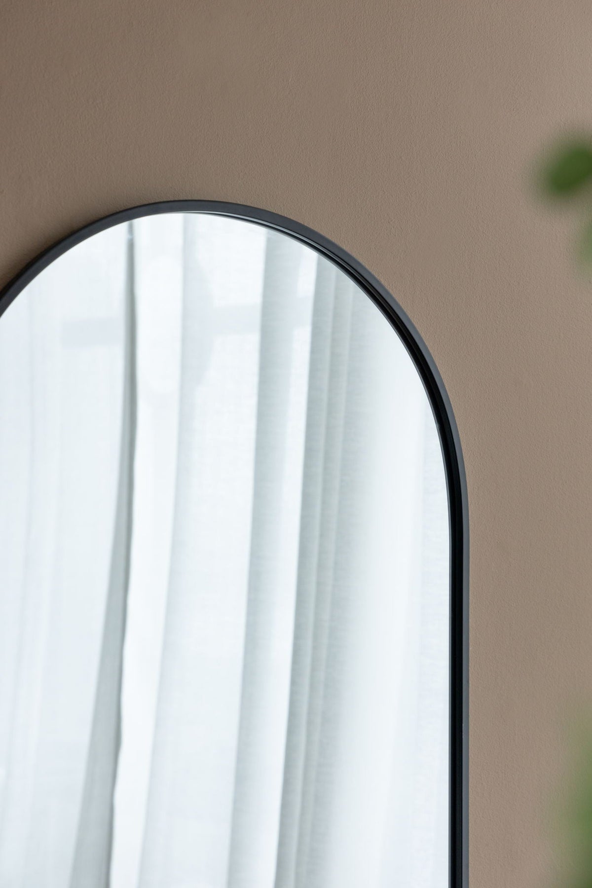 Arched metal-frame wall mirror in black with white curtains on tan wall HouseOfZazla on Tampa Home & Garden Store