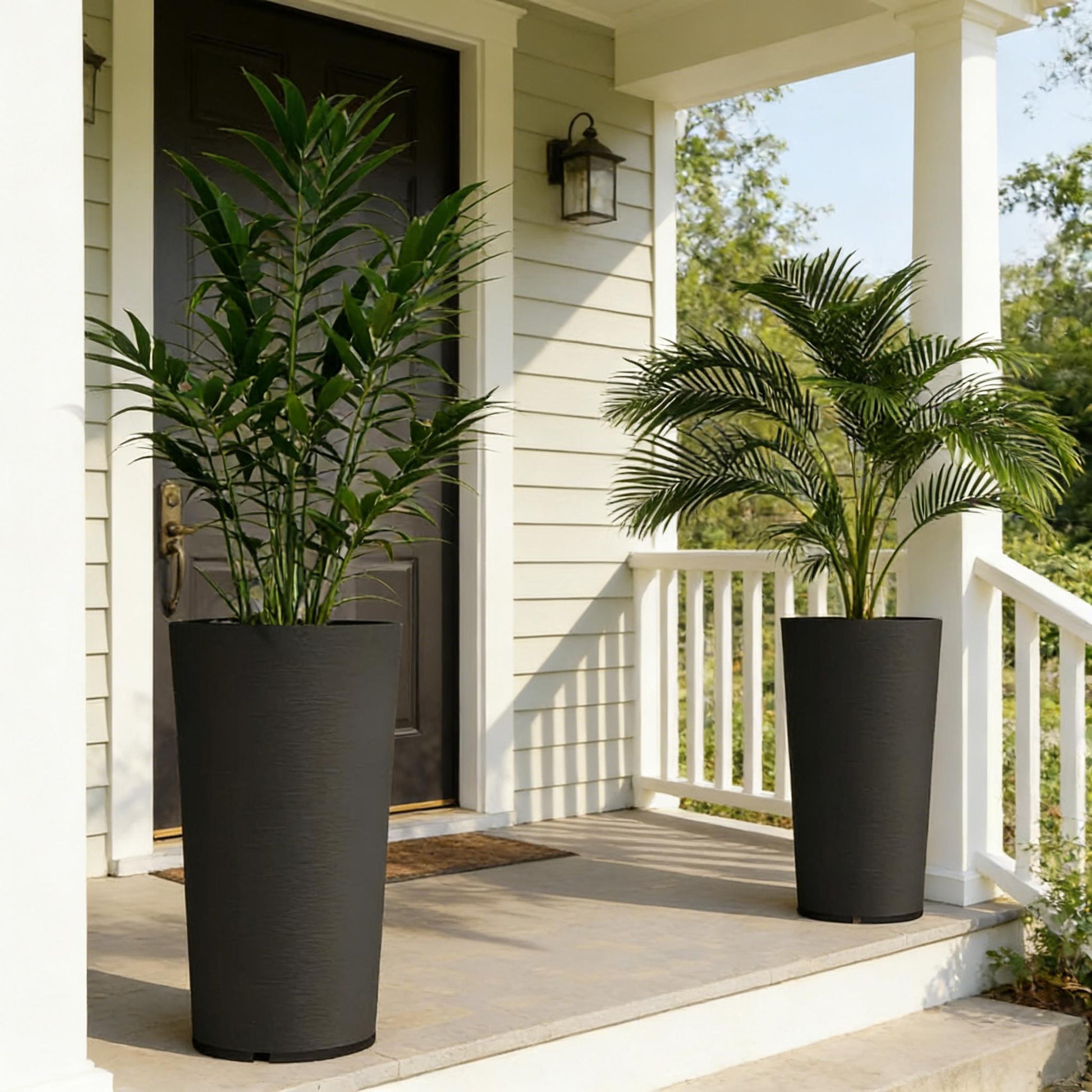Set of 2 stackable large black flower pots with tall green plants on a porch on Tampa Home & Garden Store