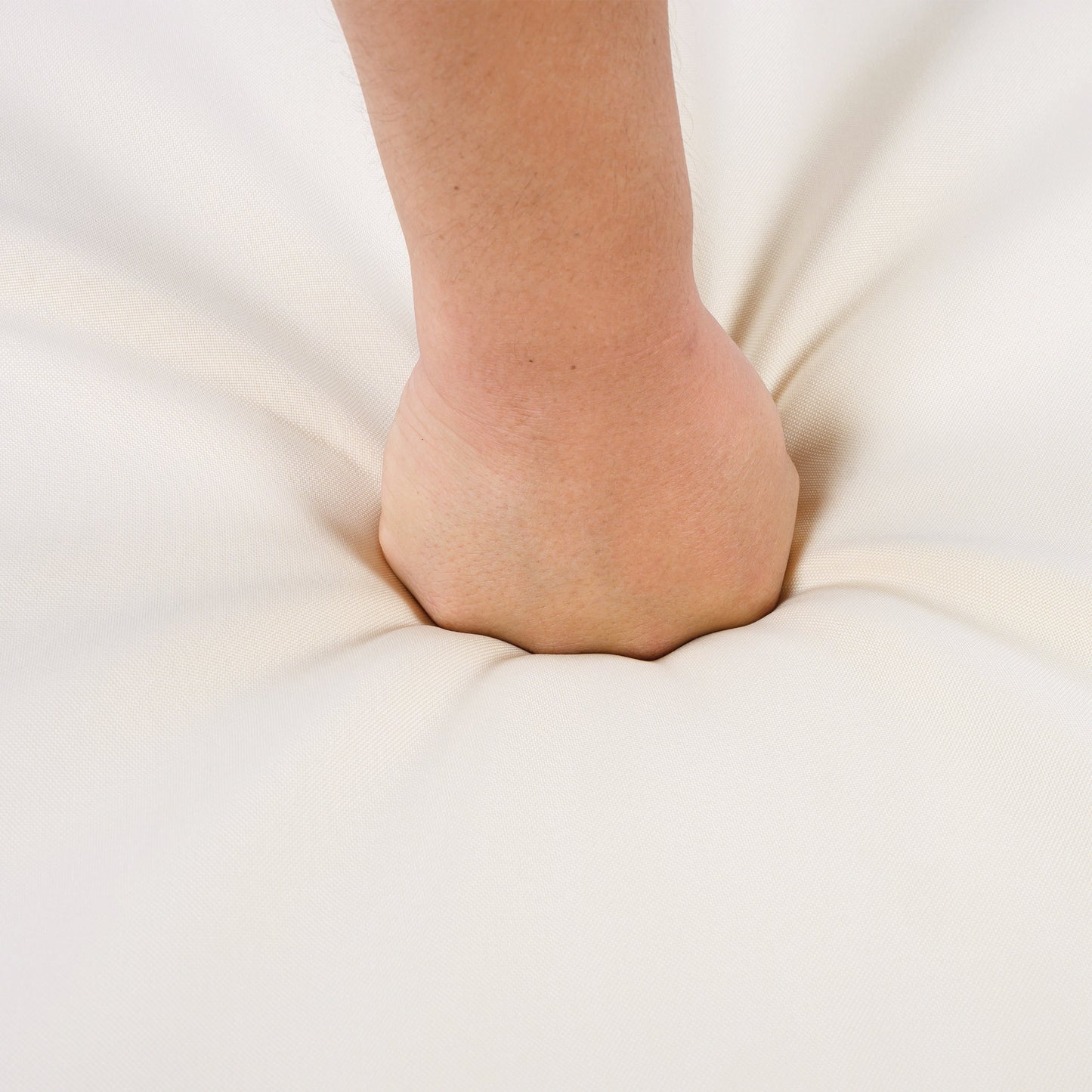 Close-up of a bare ankle resting on cream fabric background on Tampa Home & Garden Store