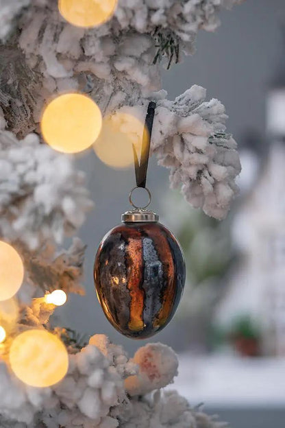 Christmas ball ornament, copper-brown glass with glaze, hanging from a snow-dusted tree branch on Tampa Home & Garden Store