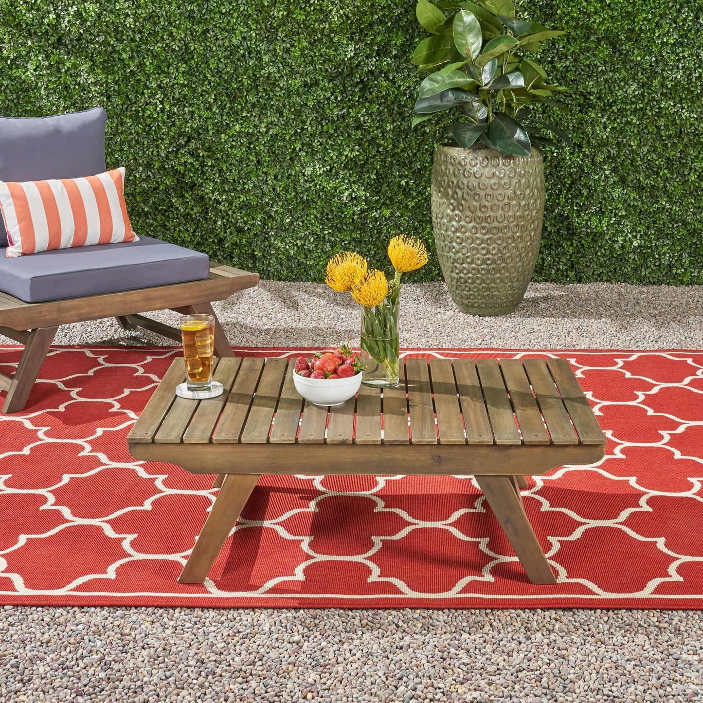 Outdoor Acacia Wood Coffee Table With Open Slat Design in a patio setting beside a grey sofa and pillow on Tampa Home & Garden Store