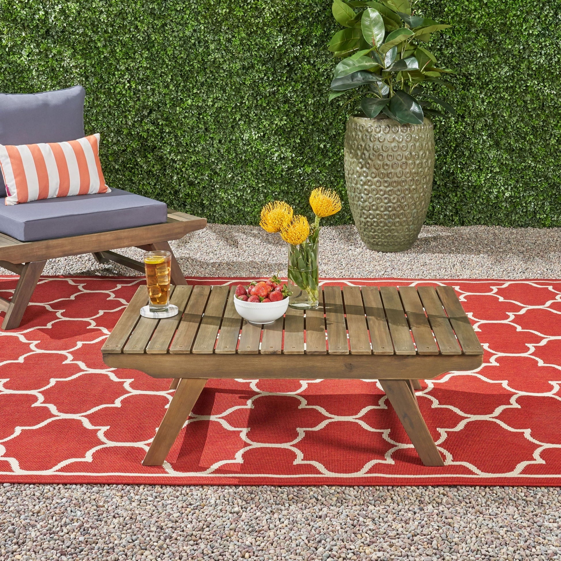 Outdoor Acacia Wood Coffee Table With Open Slat Design in a patio setting beside a grey sofa and pillow on Tampa Home & Garden Store