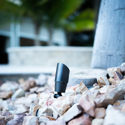 Outdoor spotlight stake by Kings Outdoor Lighting, black metal flood light among rocks on Tampa Home & Garden Store
