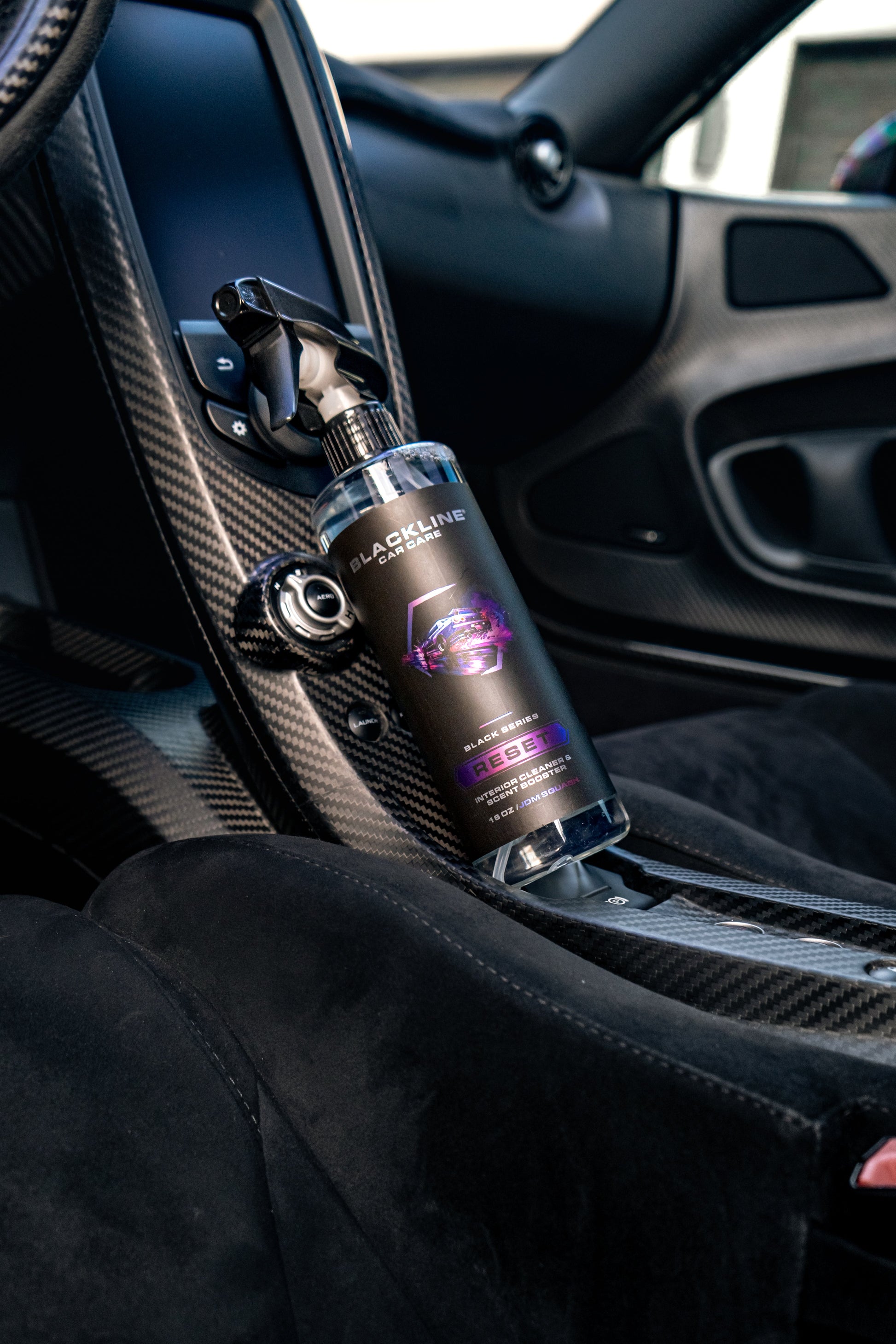 Blackline RESET interior cleaner & scent booster spray bottle in a carbon fiber car cabin on Tampa Home & Garden Store