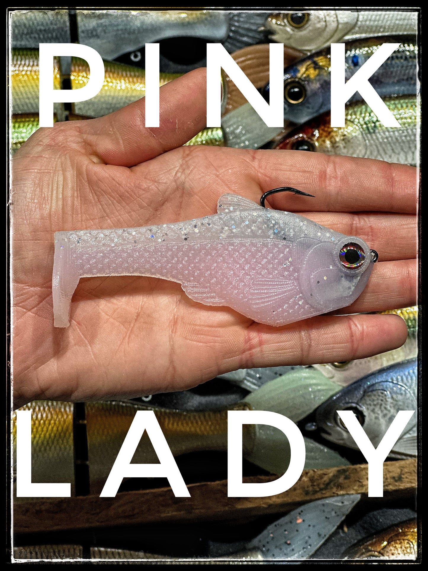 4.5 inch Nacho boot-tail soft swimbait by Bull Shad Swimbaits; pale pink translucent with glitter, single black hook visible on hand on Tampa Home & Garden Store