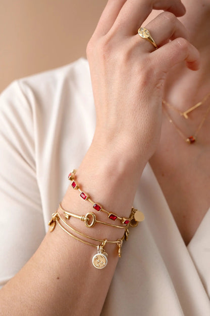 July Emerald Cut Bangle bracelet by Alex and Ani, gold-tone with red stones, stacked on wrist on Tampa Home & Garden Store