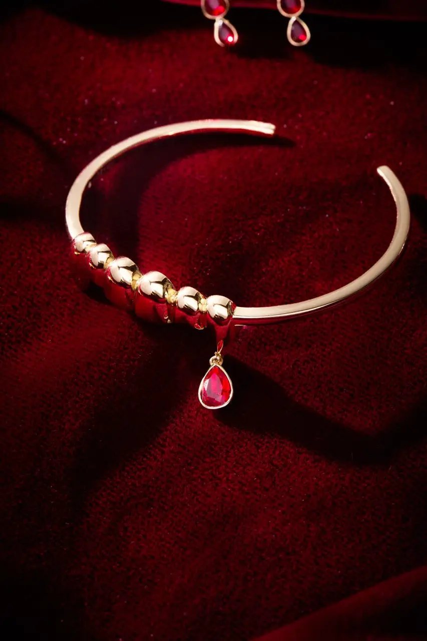 Gold vampire teeth cuff bracelet with beaded focal and red teardrop charm on red velvet on Tampa Home & Garden Store