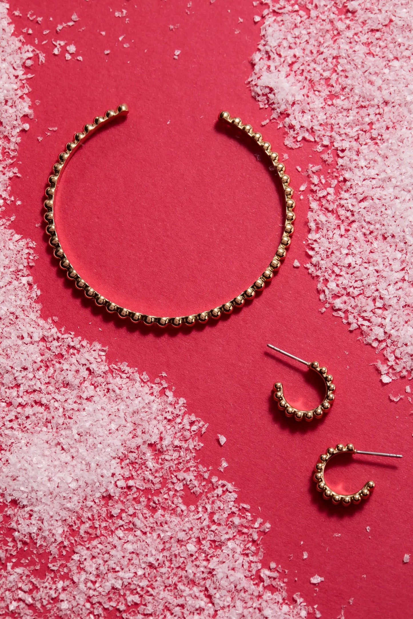 Gold-tone beaded cuff bracelet on red backdrop on Tampa Home & Garden Store