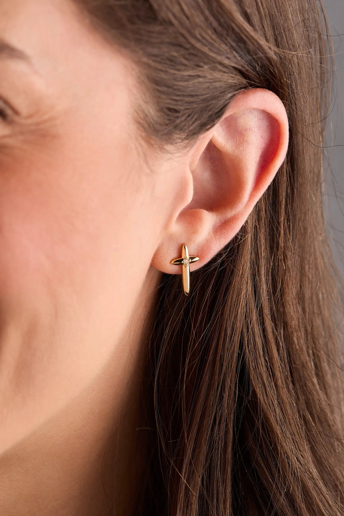 Gold-tone cross stud earring on ear, minimalist chic accessory on Tampa Home & Garden Store