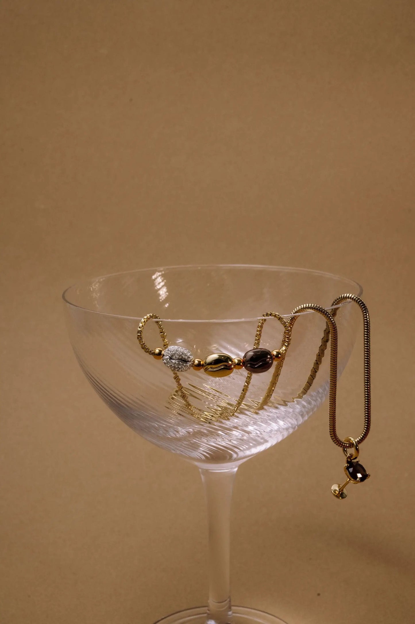 Coffee Bean Bolo Bracelet with gold-tone beads and brown coffee-bean charms on glass coupe bowl on Tampa Home & Garden Store