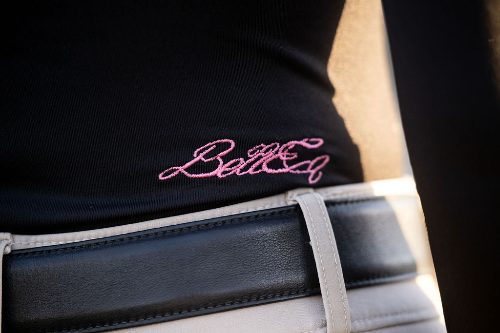 POPPI X Equestrian Top sun top in black with pink BellEq embroidery, shown with a white belt on Tampa Home & Garden Store