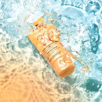 Nuxe Sun Cream for Face SPF30 50ml orange tube floating in water splash on Tampa Home & Garden Store