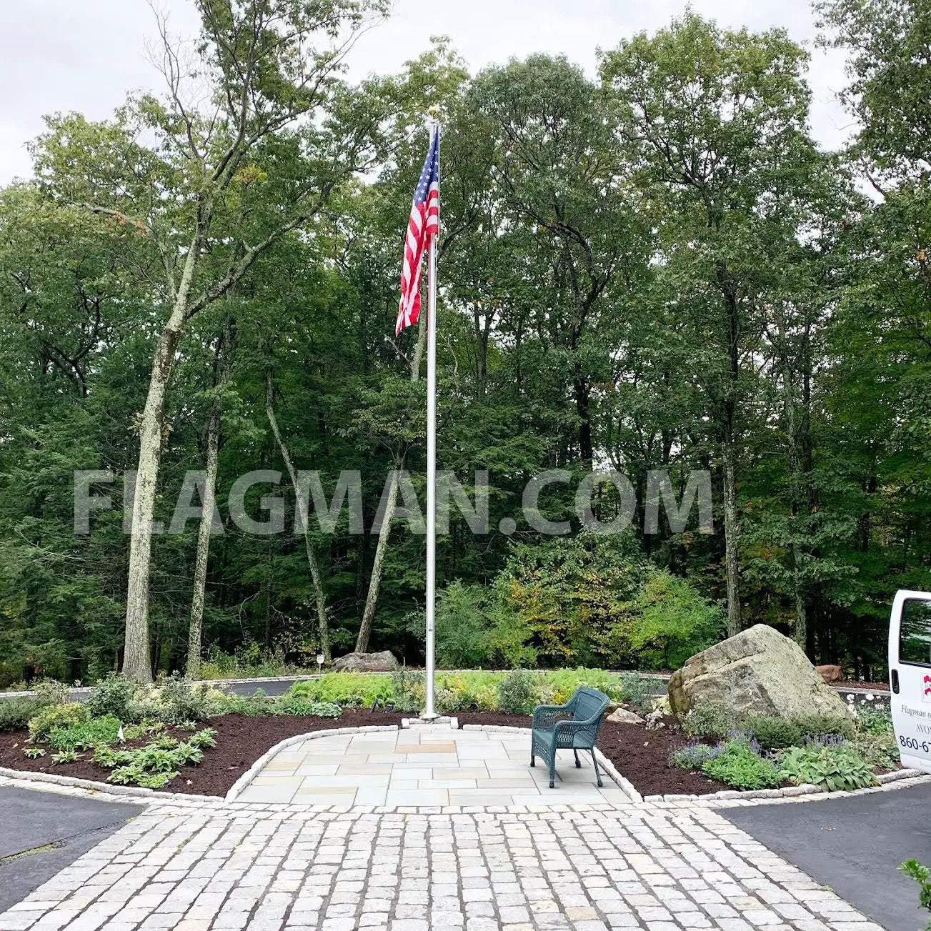 Aluminum flagpole with external rope holding American flag in a landscaped circular plaza on Tampa Home & Garden Store