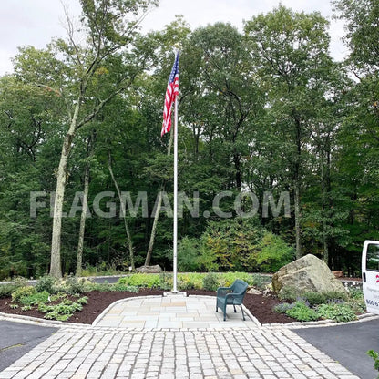 Aluminum flagpole with external rope holding American flag in a landscaped circular plaza on Tampa Home & Garden Store