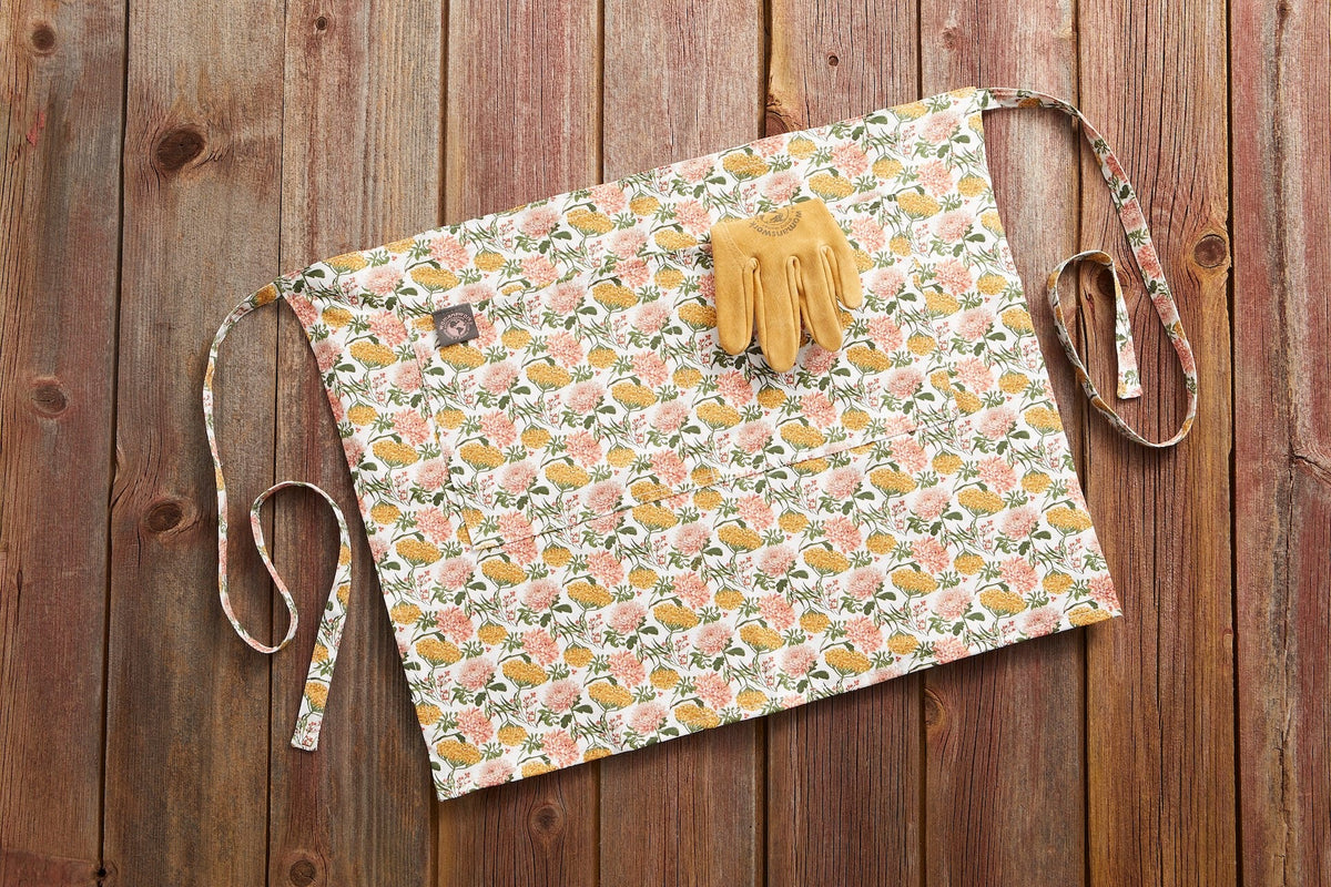 Gardener's Half Apron by Womanswork, floral pink print with ties; pair of yellow gloves on Tampa Home & Garden Store