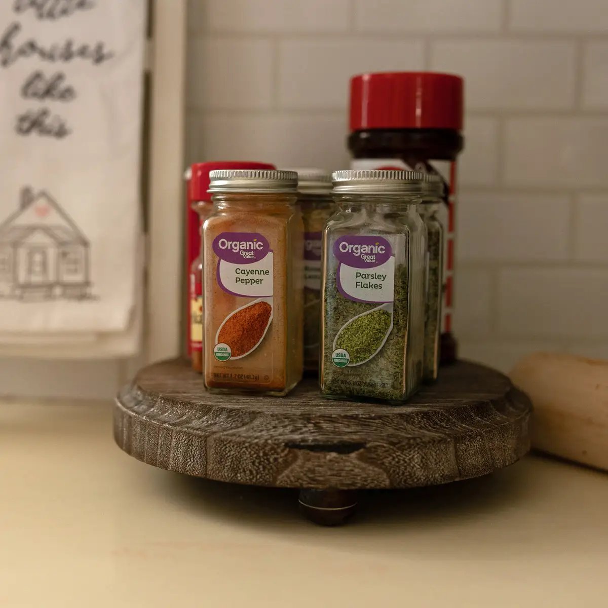 Rustic round wood pedestal tray holding four labeled spice jars on a kitchen counter on Tampa Home & Garden Store