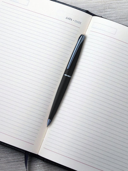 ATX Basalt Black ballpoint pen with blue PVD clip by A.T. Cross on lined notebook page on Tampa Home & Garden Store