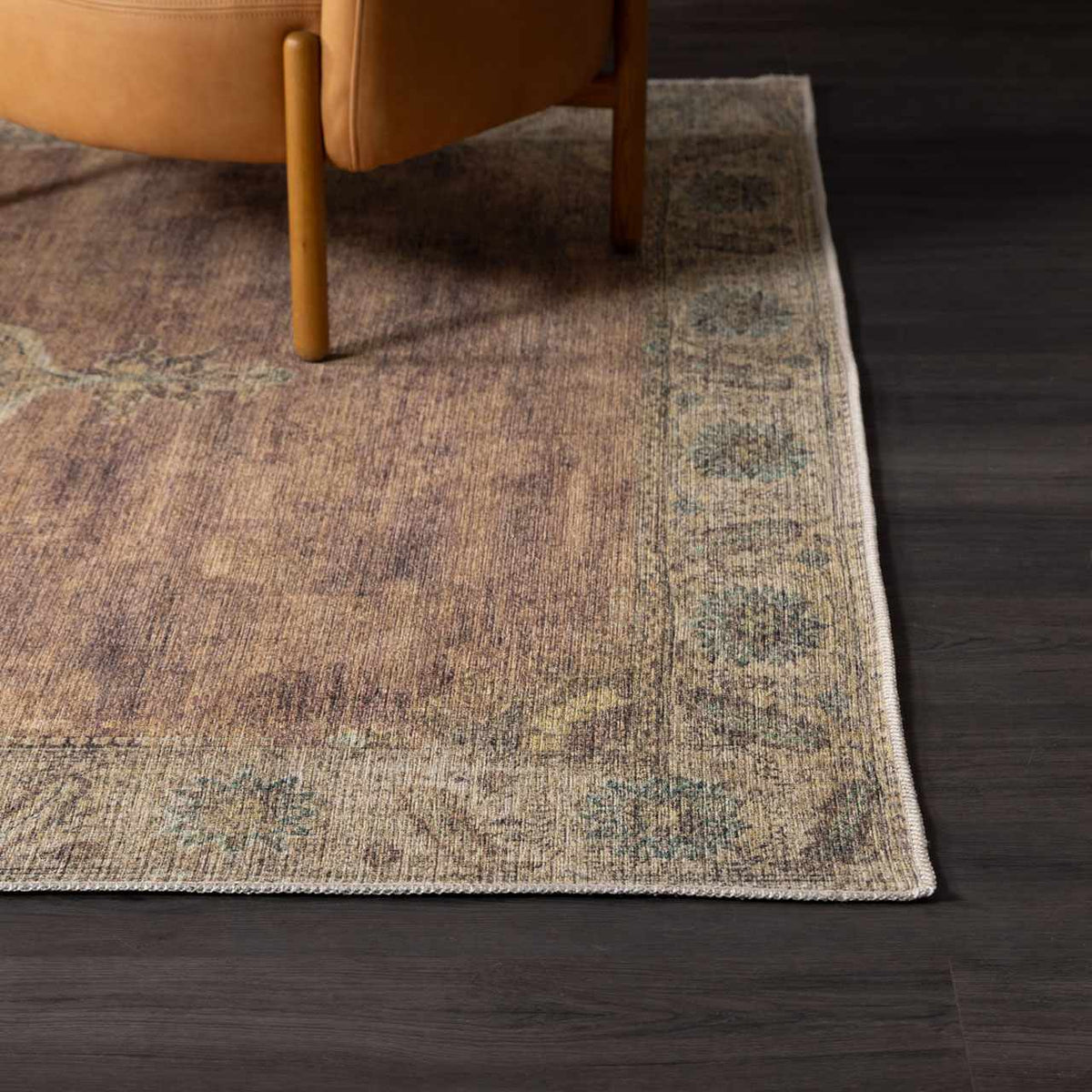 Powhatan washable area rug in brown tones with blue-green border under chair on dark floor on Tampa Home & Garden Store