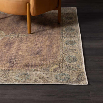 Powhatan washable area rug in brown tones with blue-green border under chair on dark floor on Tampa Home & Garden Store