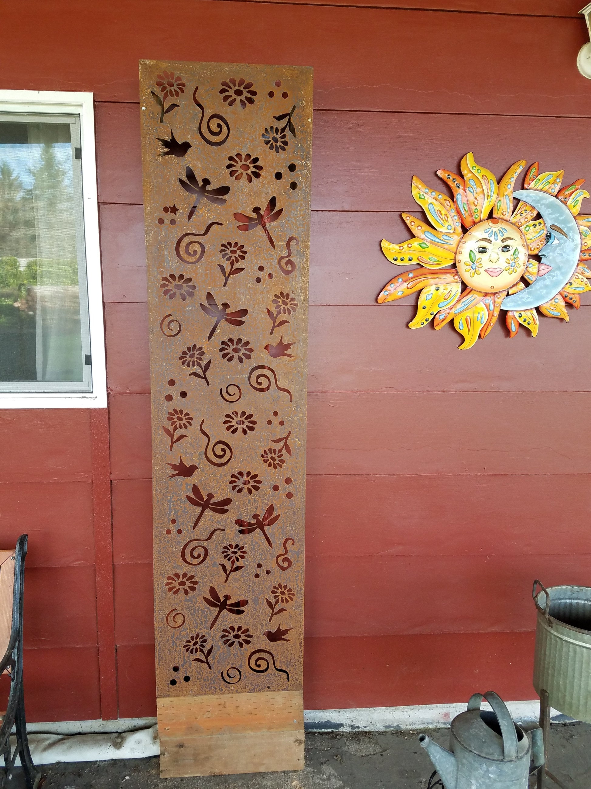 Rusted-steel outdoor privacy screen panel with dragonfly and floral cutouts beside sun wall art on Tampa Home & Garden Store