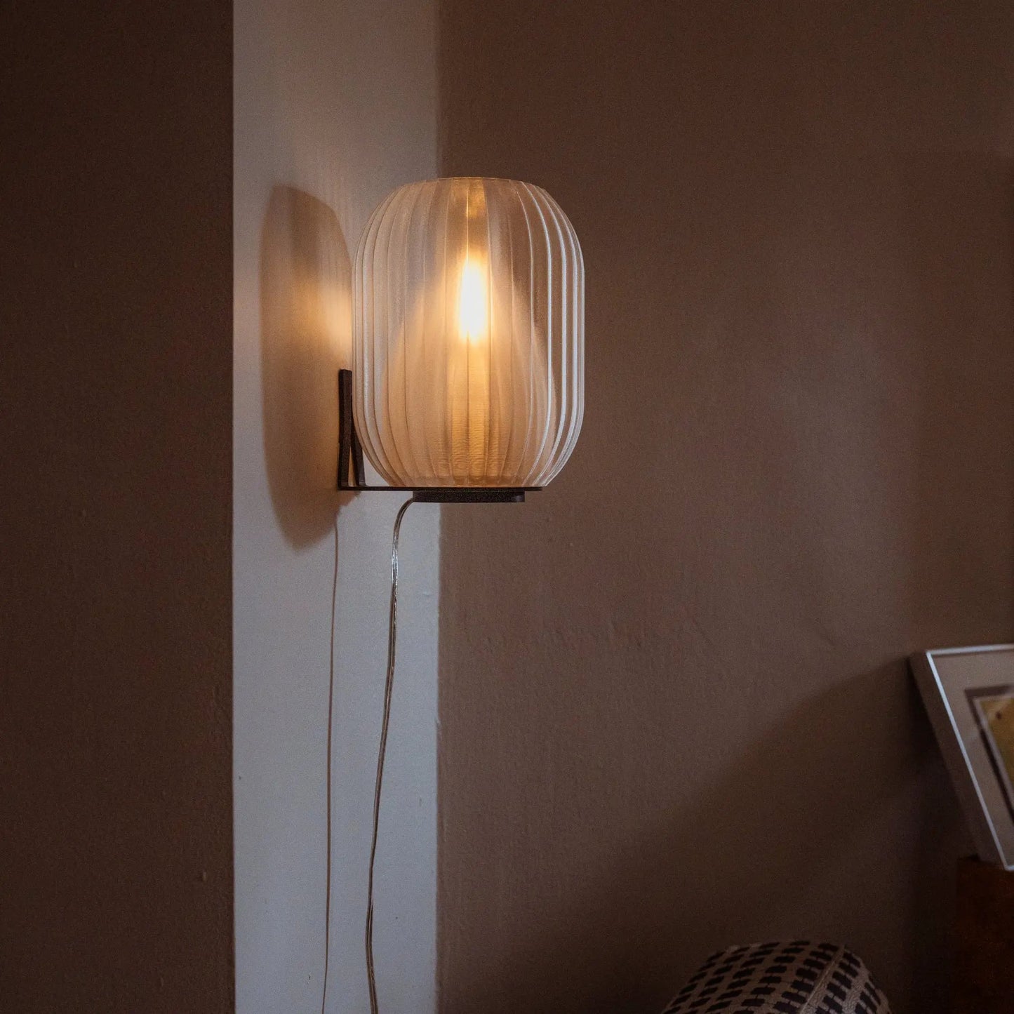 Allium Sconce wall light by Wooj Design with ribbed glass shade and warm amber glow on wall on Tampa Home & Garden Store